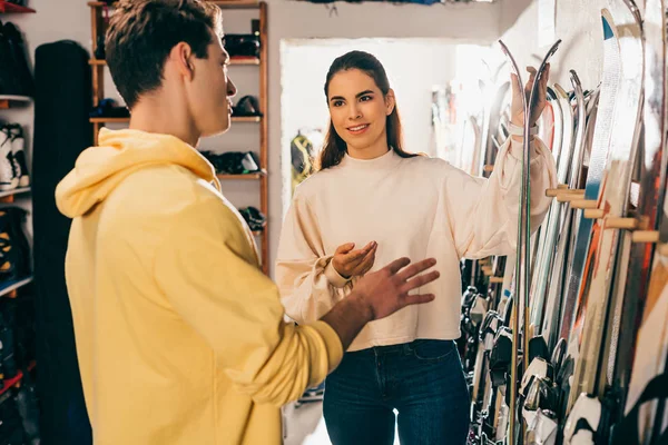 Operaio sorridente che mostra sci al cliente e parla in officina — Foto stock