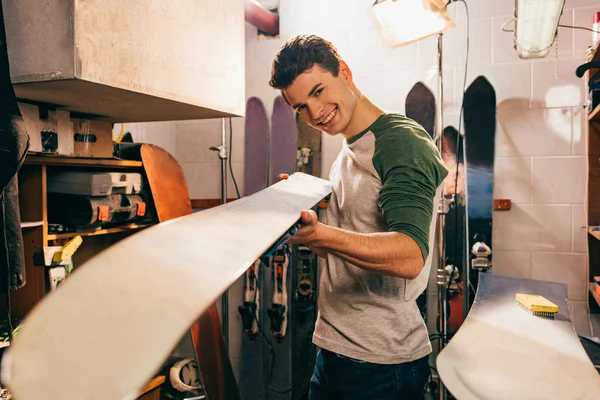 Selective focus of worker holding snowboard in repair shop — Stock Photo