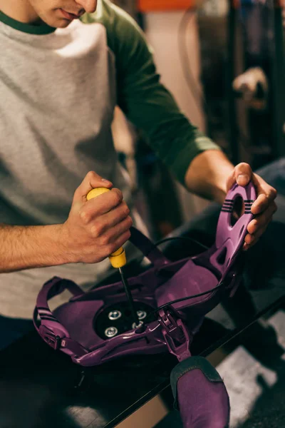 Cropped view of worker screwing snowboard binding to snowboard in repair shop — Stock Photo