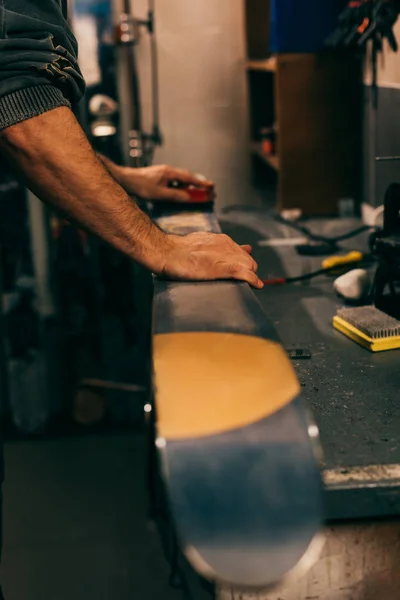 Обрізаний вид на працівника, використовуючи пензлик на лижах у ремонтному магазині — стокове фото