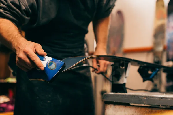 Обрезанный вид работника с помощью воскового утюга на лыжах в ремонтной мастерской — стоковое фото