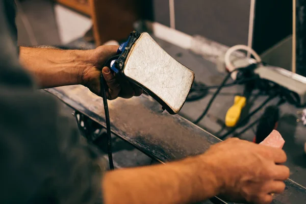 Cropped view of worker holding wax iron in repair shop — Stock Photo