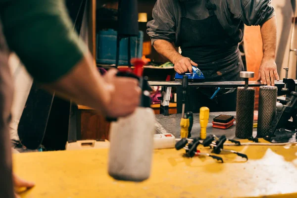 Cropped view of worker using wax iron on ski in repair shop — Stock Photo