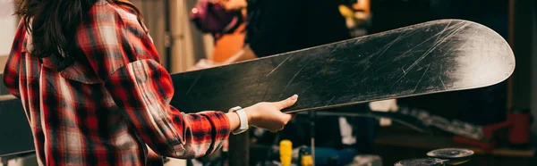 Panoramic shot of worker holding ski in repair shop — Stock Photo