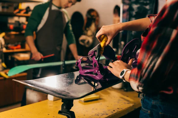 Cropped view of worker screwing snowboard binding to snowboard in repair shop — Stock Photo