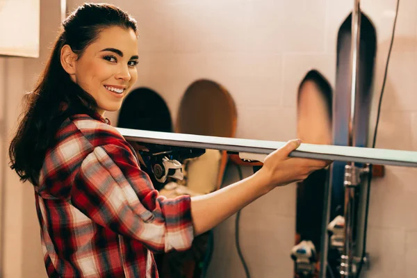 Smiling worker holding ski and looking at camera in repair shop — Stock Photo