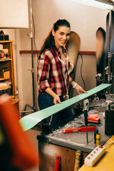 Smiling worker holding ski and looking at camera in repair shop — Stock Photo