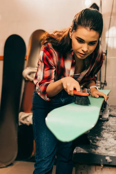 Atractivo trabajador limpieza esquí con cepillo en taller de reparación - foto de stock