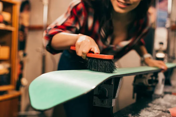 Vue recadrée du travailleur souriant nettoyant le ski avec une brosse dans l'atelier de réparation — Photo de stock