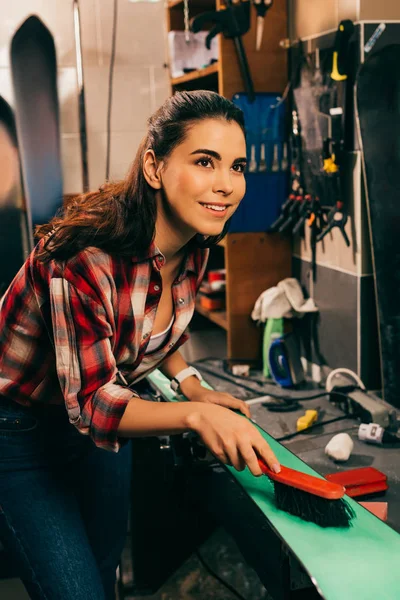 Sorridente lavoratore pulizia sci con pennello in officina — Foto stock