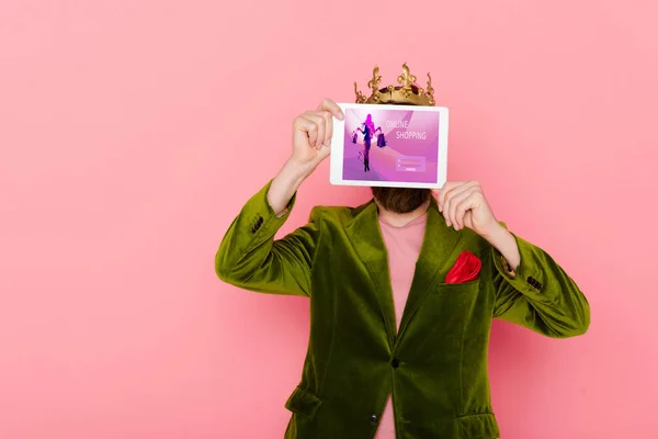 Hombre con corona celebración tableta digital con aplicación de compras en línea aislado en rosa — Stock Photo