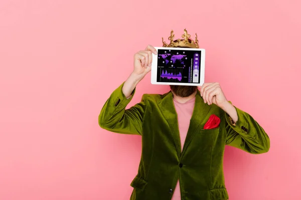 Man with crown holding digital tablet with online business division app isolated on pink — Stock Photo