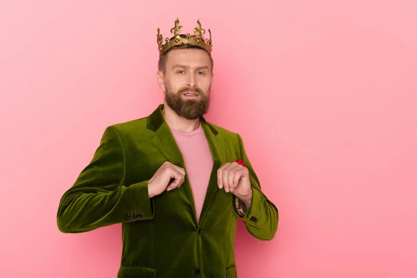 Handsome man with crown in velour jacket looking at camera on pink background — Stock Photo