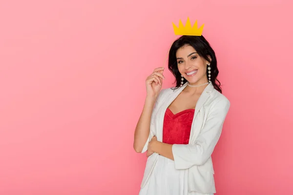 Smiling woman holding paper crown looking at camera on pink background — Stock Photo