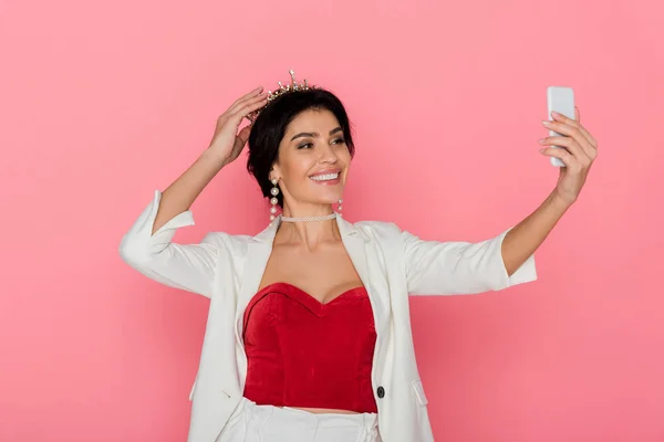 Lächelnde Frau mit Krone macht Selfie auf rosa Hintergrund — Stockfoto