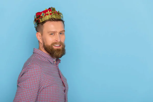 Smiling man with crown looking at camera isolated on blue — Stock Photo