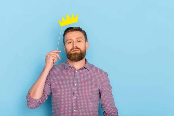Handsome man in shirt holding paper crown on blue background — Stock Photo