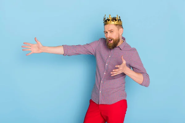 Uomo scioccato con corona che punta con mano su sfondo blu — Foto stock