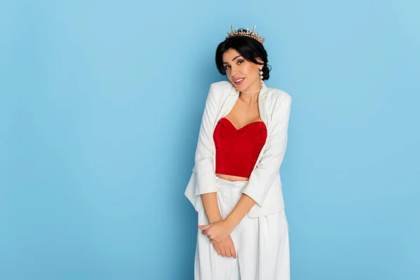 Shy woman with crown looking at camera on blue background — Stock Photo