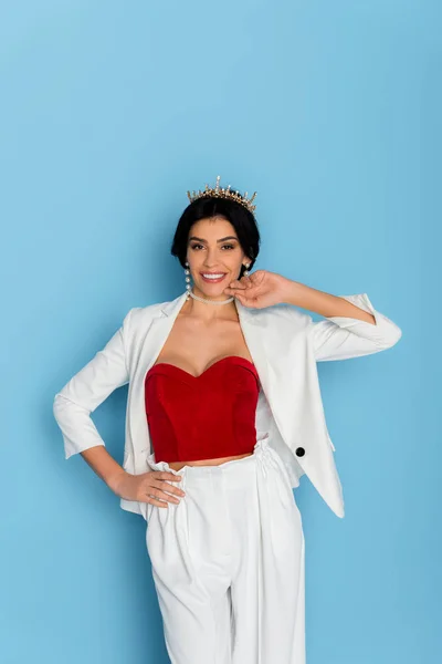 Mujer sonriente con corona mirando a la cámara sobre fondo azul — Stock Photo
