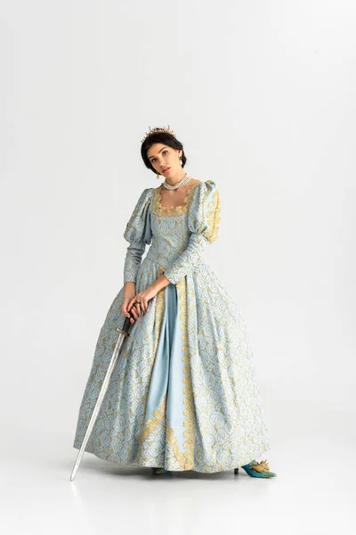 Atractiva reina con corona sosteniendo espada sobre fondo gris — Stock Photo