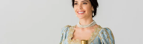 Panoramic shot of smiling queen holding cup isolated on grey — Stock Photo