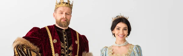 Panoramic shot of smiling queen and king with crowns isolated on grey — Stock Photo