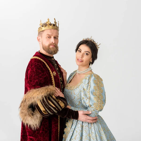 Smiling queen and king with crowns hugging isolated on grey — Stock Photo