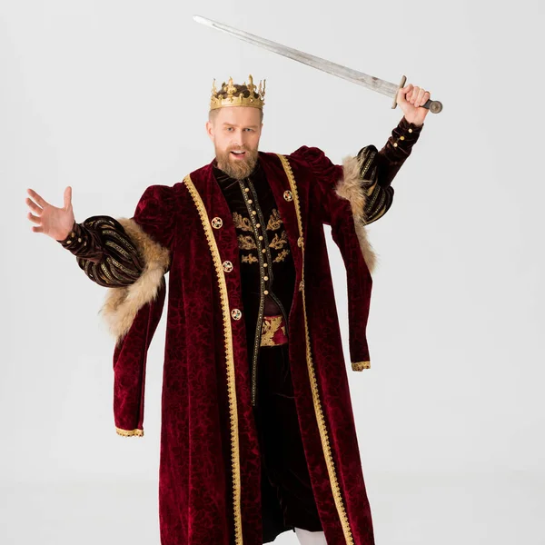 Rey enojado con corona sosteniendo espada aislada en gris - foto de stock