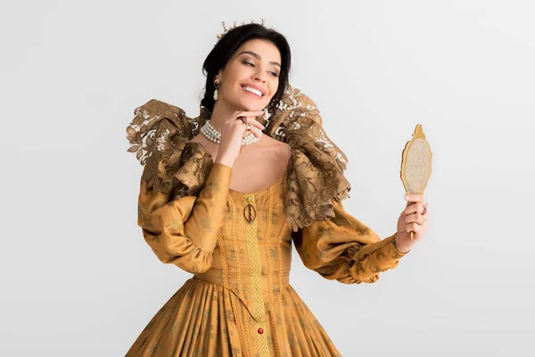 Smiling queen with crown looking at mirror isolated on grey — Stock Photo