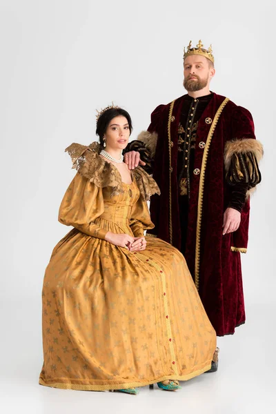 Королева и король с коронами, смотрящими в камеру на сером фоне — стоковое фото