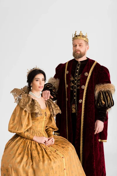 Reina y rey con coronas mirando a la cámara aislada en gris - foto de stock