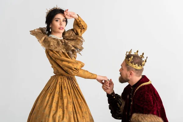 King with crown holding hand of shocked queen isolated on grey — Stock Photo