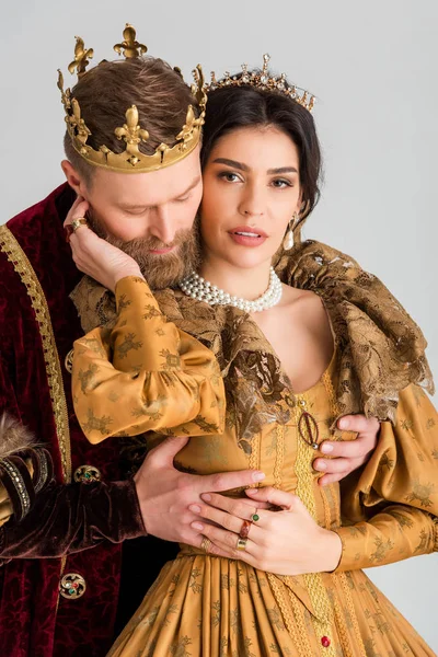 Rei com coroa abraçando rainha atraente isolado em cinza — Fotografia de Stock