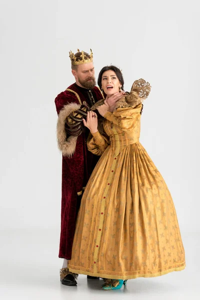 King with crown choking attractive queen on grey background — Stock Photo