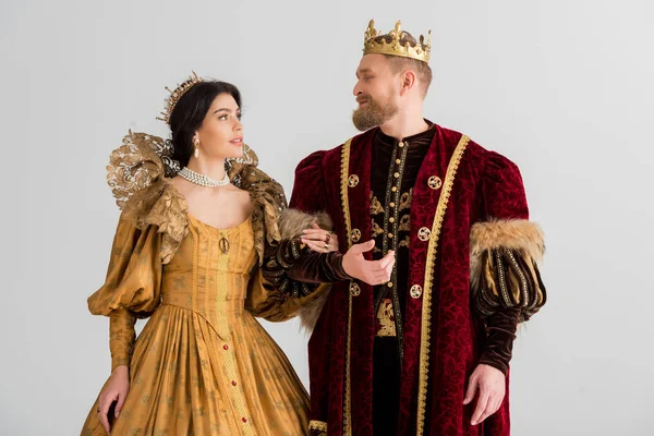 Queen and smiling king with crowns holding hands isolated on grey — Stock Photo