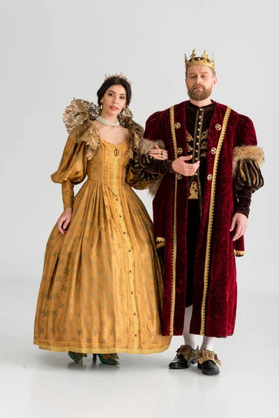 Queen and king with crowns holding hands on grey background — Stock Photo