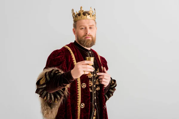 Beau roi avec couronne tenant tasse et regardant la caméra isolée sur gris — Photo de stock