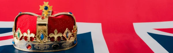 Tiro panorâmico da coroa dourada na bandeira britânica — Fotografia de Stock