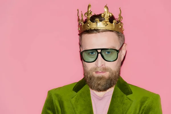 Handsome man in velour jacket and crown looking at camera isolated on pink — Stock Photo
