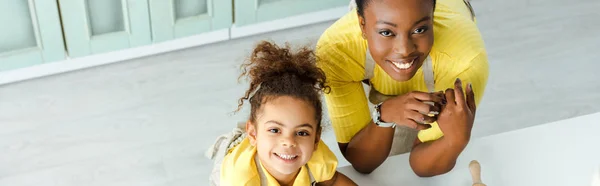 Panoramaaufnahme eines glücklichen afrikanisch-amerikanischen Kindes und seiner Mutter, die in die Kamera schauen — Stockfoto