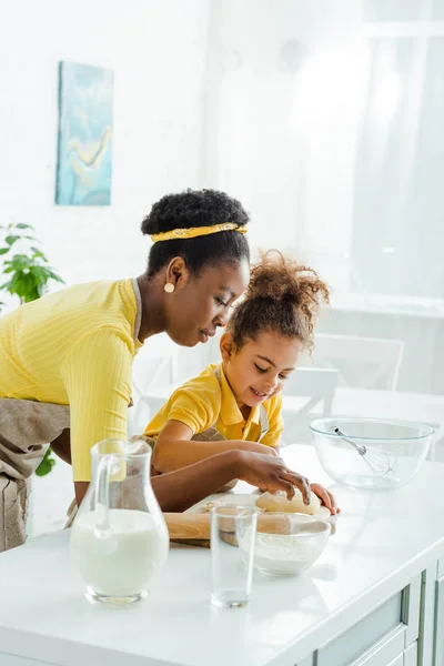 Attraktive afrikanisch-amerikanische Mutter in der Nähe von niedlichen Tochter Modellierung Knödel in der Küche — Stockfoto