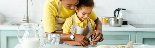 Plan panoramique de heureuse mère afro-américaine près de fille mignonne sculpter des boulettes dans la cuisine — Photo de stock