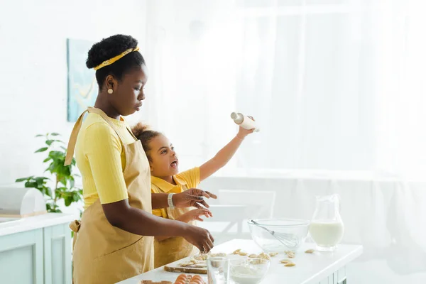 Attrayante mère afro-américaine près de fille mignonne tenant rouleau à pâtisserie — Photo de stock
