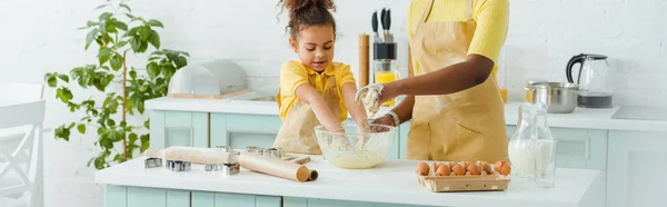 Plano panorámico de la madre afroamericana y su hija amasando masa en la cocina - foto de stock
