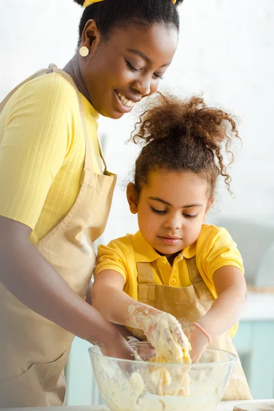 Happy african american mother and adorable daughter kneading dough — Stock Photo
