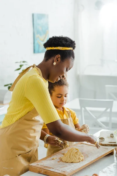 Happy african american mother and daughter kneading raw dough — Stock Photo