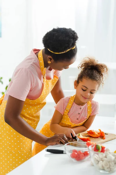 Afrikanisch-amerikanische Mutter schaut lächelnde Tochter in Küche an — Stockfoto