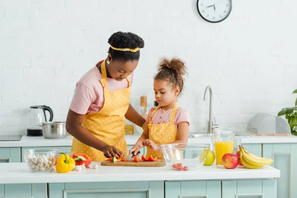 African american mother and daughter cutting bell pepper on cutting board — Stock Photo