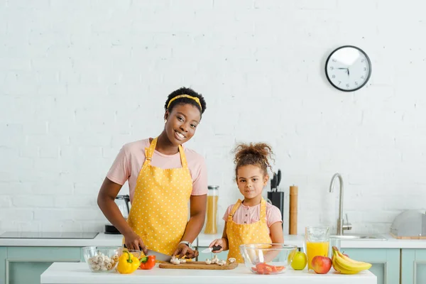 Felice donna africana americana e figlia vicino ingredienti in cucina — Foto stock